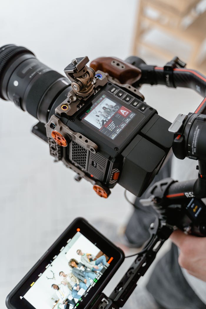 who-we-are-img Close-up of a modern video camera setup capturing a group in an indoor setting.